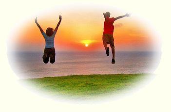 Young man and woman leaping into the air at sunrise.