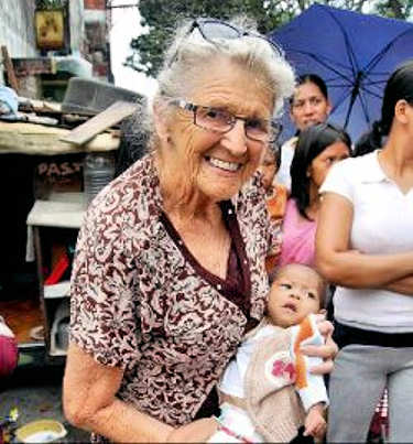 Elderly woman holding a baby and helping the needy in her in her community.