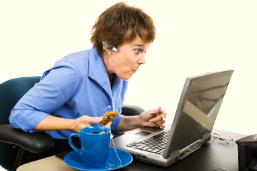 Advice lady sitting at a desk looking at a computer screen.