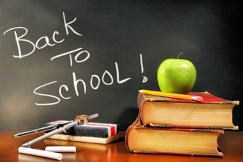 Back to School message on the blackboard, with books and one nice apple on the teachers desk.