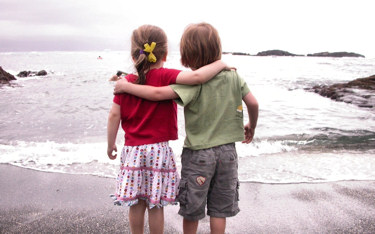 Boy and girl looking at the ocean from the beach.