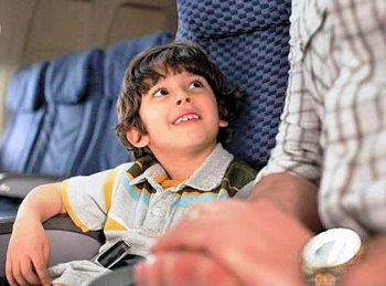 A young boy talking to a man on an airplane.