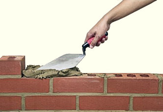 Man laying bricks with motar.