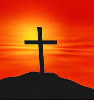 A dark cross on a dark hill with a beautiful yellow-orange-red background.
