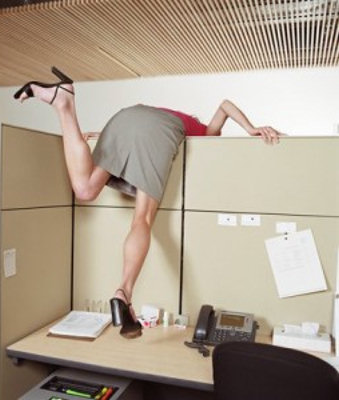 Woman escaping over the wall of her office cubicle.
