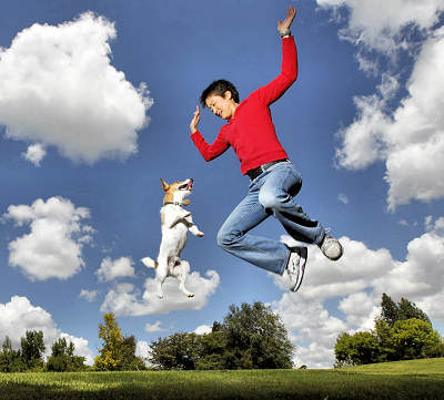 Man and dog jumping up into the air.