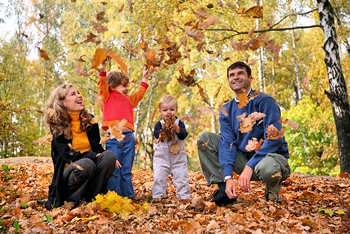 Mother, father, and two young childern enjoying the colorful Fall leaves.