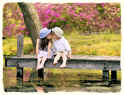 First kiss, young boy and girl - sitting on a boat dock in the country.