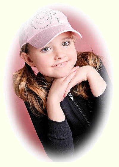 Cute young girl, with a ponytail, wearing a pink baseball cap.