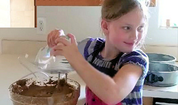 Young girl making an anniversary chocolate cake for her parents.