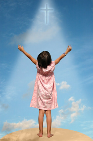 Young girl raising her hands in praise towards a cross in the sky.