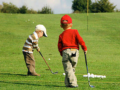 Two young boys playing golf.