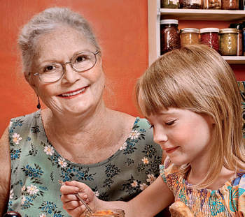 Grandmother and granddaughter at the kitchen table enjoying freshly baked cookies.