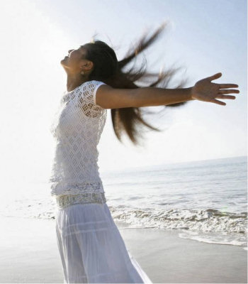 Woman on the beach with her head and arms raise-up to the sky.