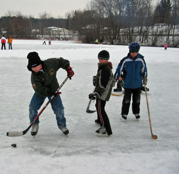 Kids playing hockey outdoors.