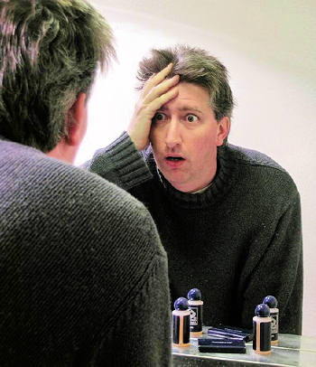 Man with concerned expression looking at a mirror.