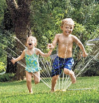 Young boy and girl cooling off with a sprinkler.