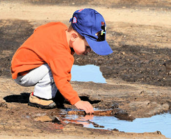 Little boy playing in the dirt and water.