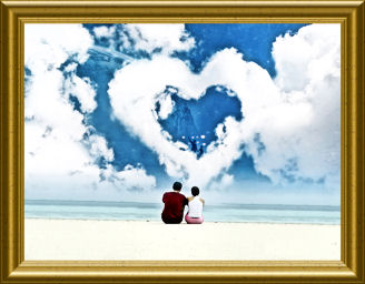 Couple sitting on a beach gazing up at a heart shaped cloud.