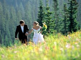 Bride and groom running in forest field.