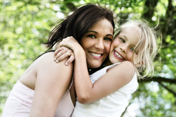 Mother holding a beautiful smiling daughter in her arms.