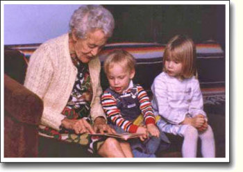 Elderly lady helping two childern read.