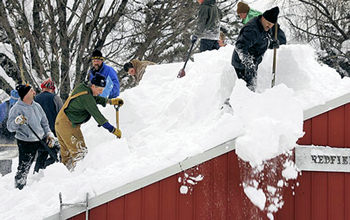 Neighborhood heroes shoveling snow off of a roof.