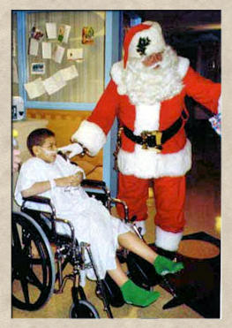 Santa helping a sick child in a wheelchair.