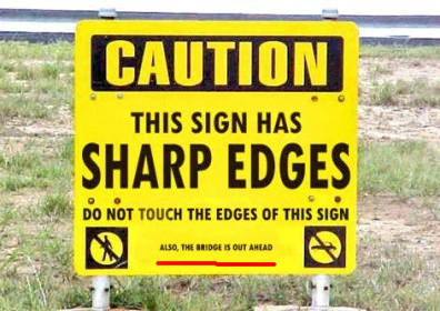 A yellow and black sign: 'Caution, This Sign Has Sharp Edges'