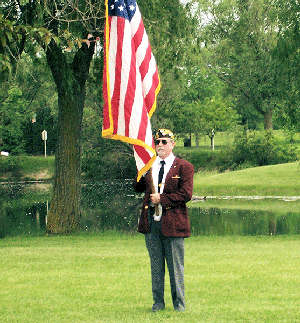 Old soldier at the park, proudly holding the American flag.