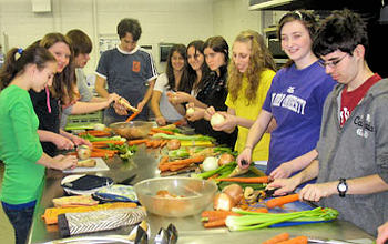 Male and female teens, voluntarily, helping prepare food for the needy at a soup kitchen.