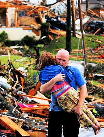 Young girl being carried from the tornado wreckage by a rescuer.
